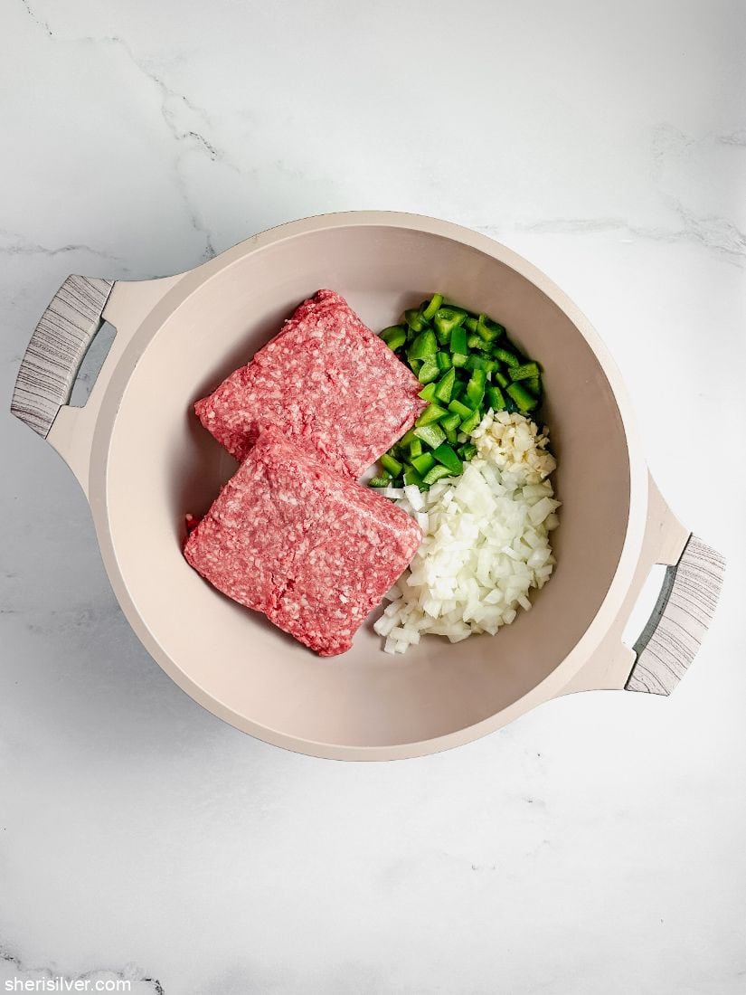 pot filled with ground beef chopped onion and chopped green peppers