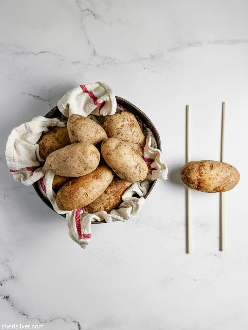 pan filled with potatoes next to a potato on top of two chopsticks