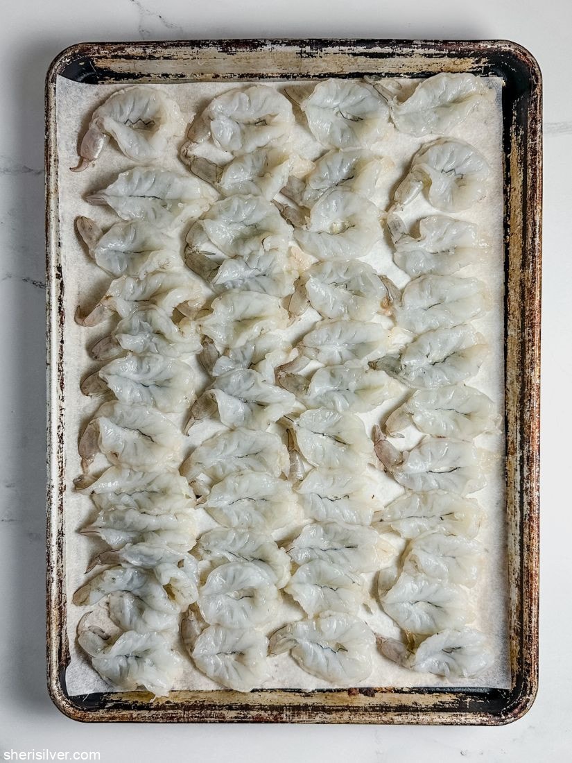 butterflied shrimp on a parchment lined baking sheet