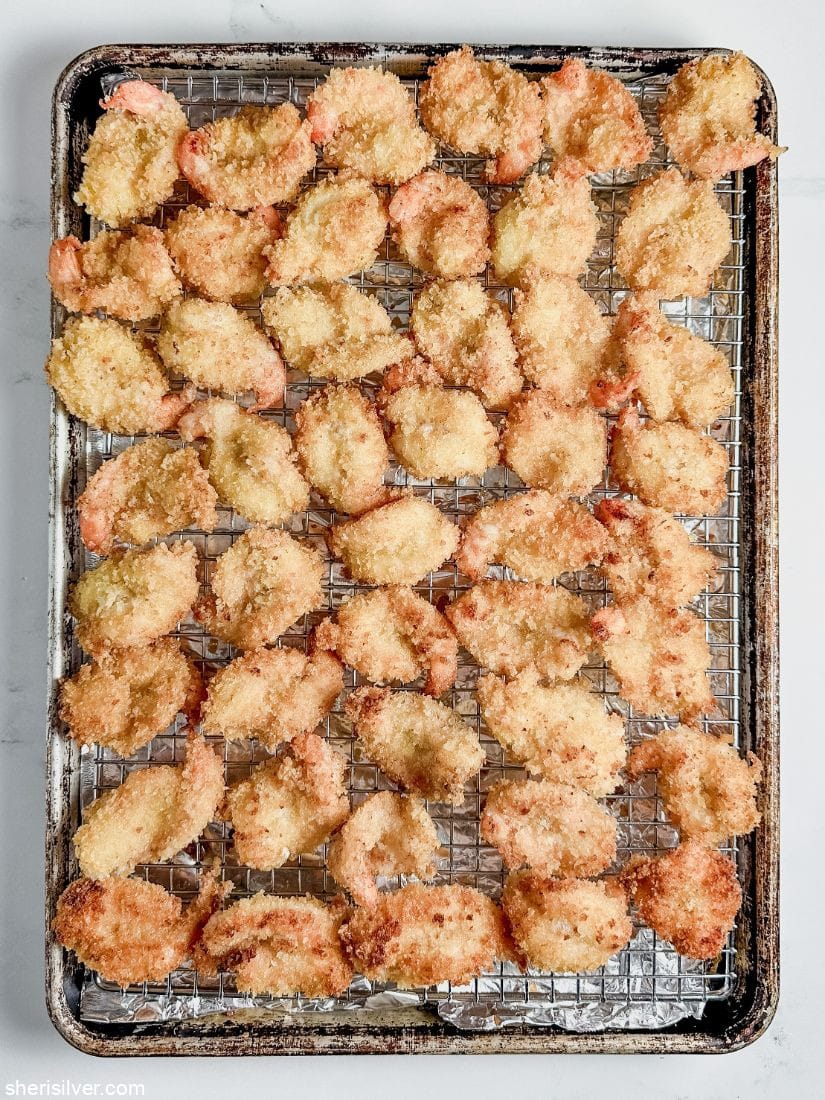 fried breaded shrimp on a wire rack set over a baking sheet