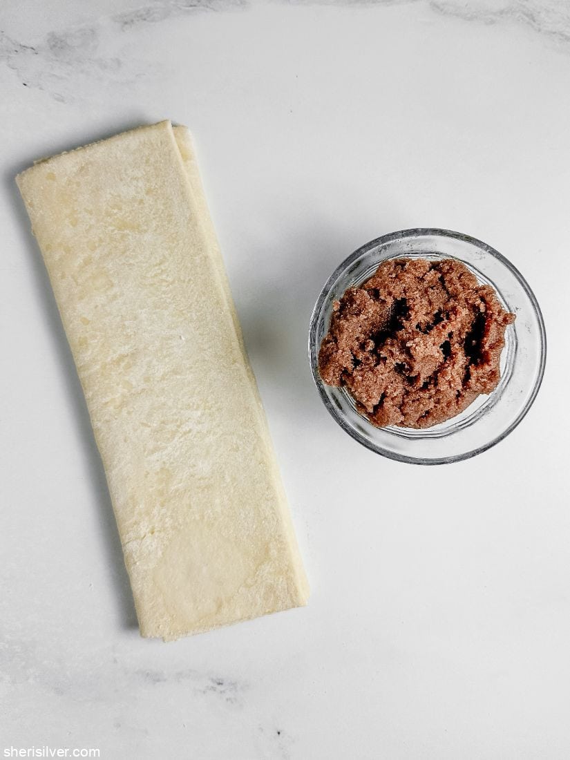 puff pastry spirals on a safety grater on crumpled wax paper