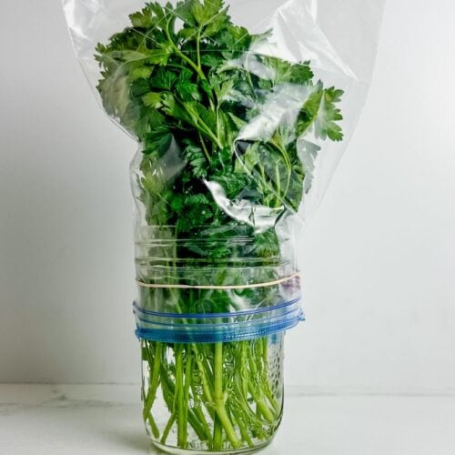 italian parsley in a mason jar covered with a ziploc bag
