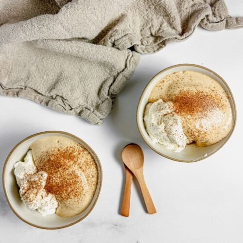 Dalgona mousse and whipped cream in ceramic bowls with wooden spoons