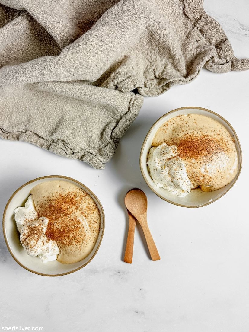 Dalgona mousse and whipped cream in ceramic bowls with wooden spoons