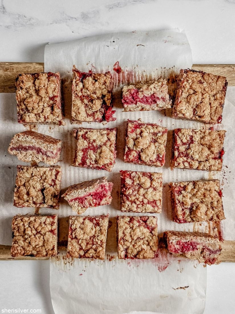 Raspberry oat squares in a parchment lined wooden board