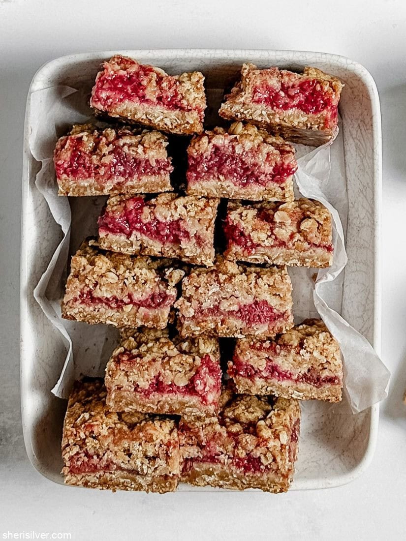 Raspberry oat squares in a parchment lined ceramic dish