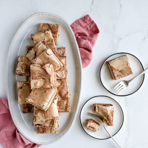 Cranberry curd mud hen bars on a white ceramic platter and white plates