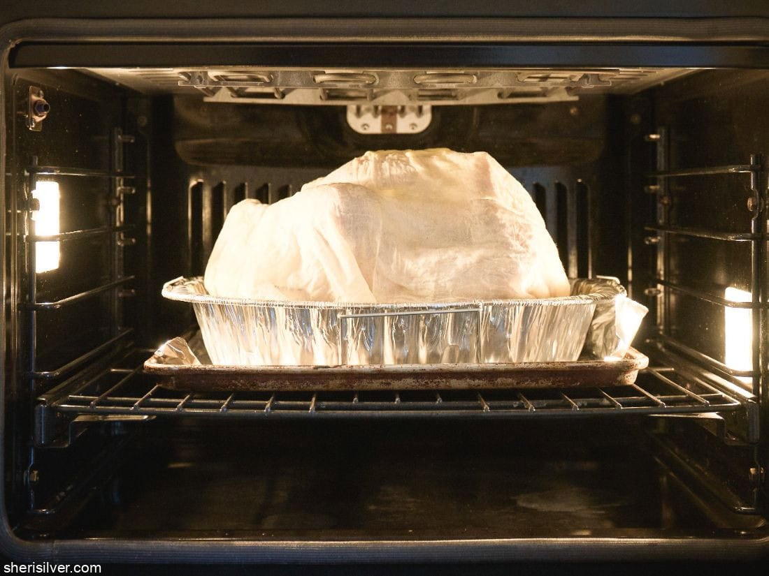 Thanksgiving turkey covered with cheesecloth in the oven
