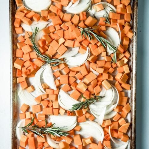butternut squash on a baking sheet with onions and rosemary