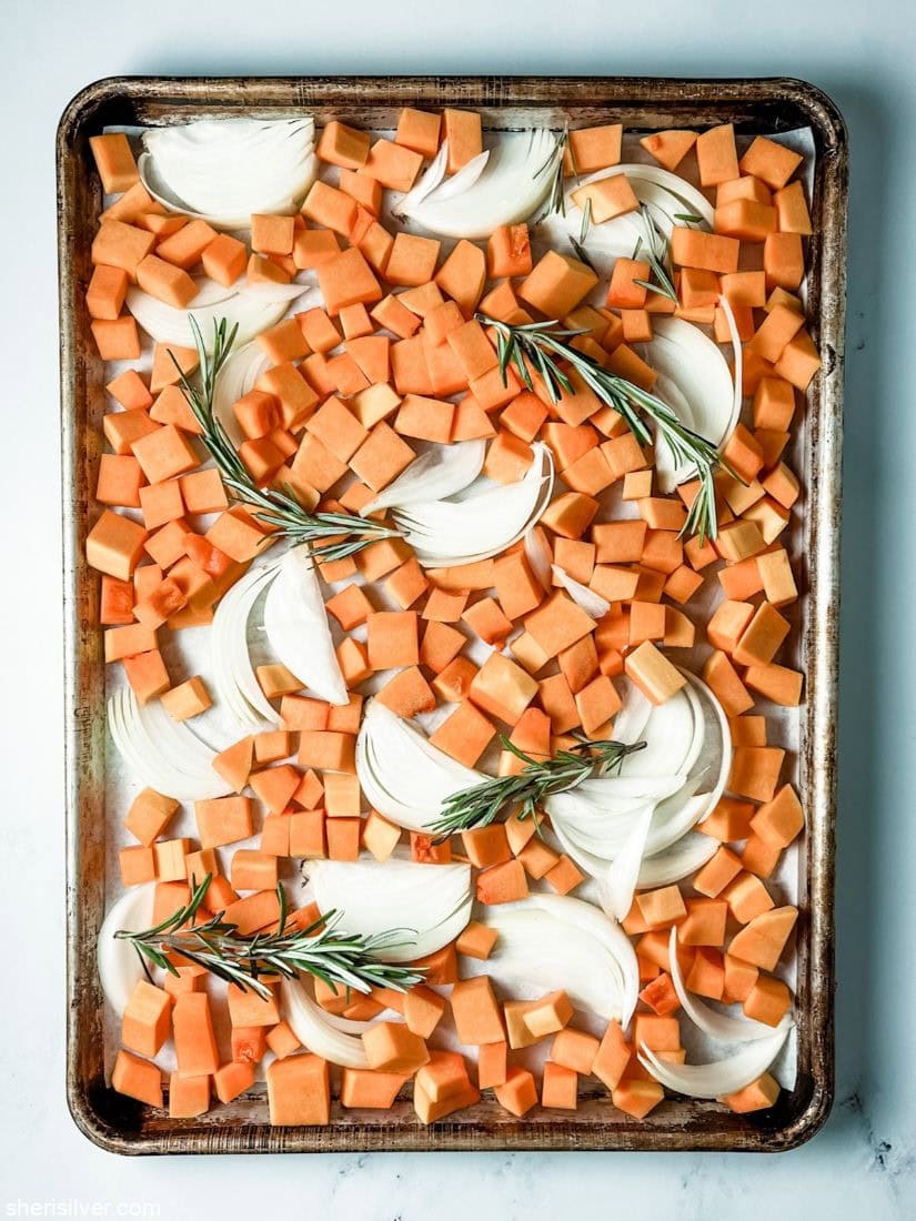 butternut squash on a baking sheet with onions and rosemary