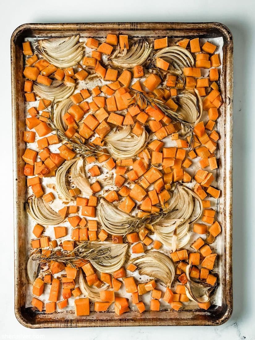 butternut squash on a baking sheet with onions and rosemary