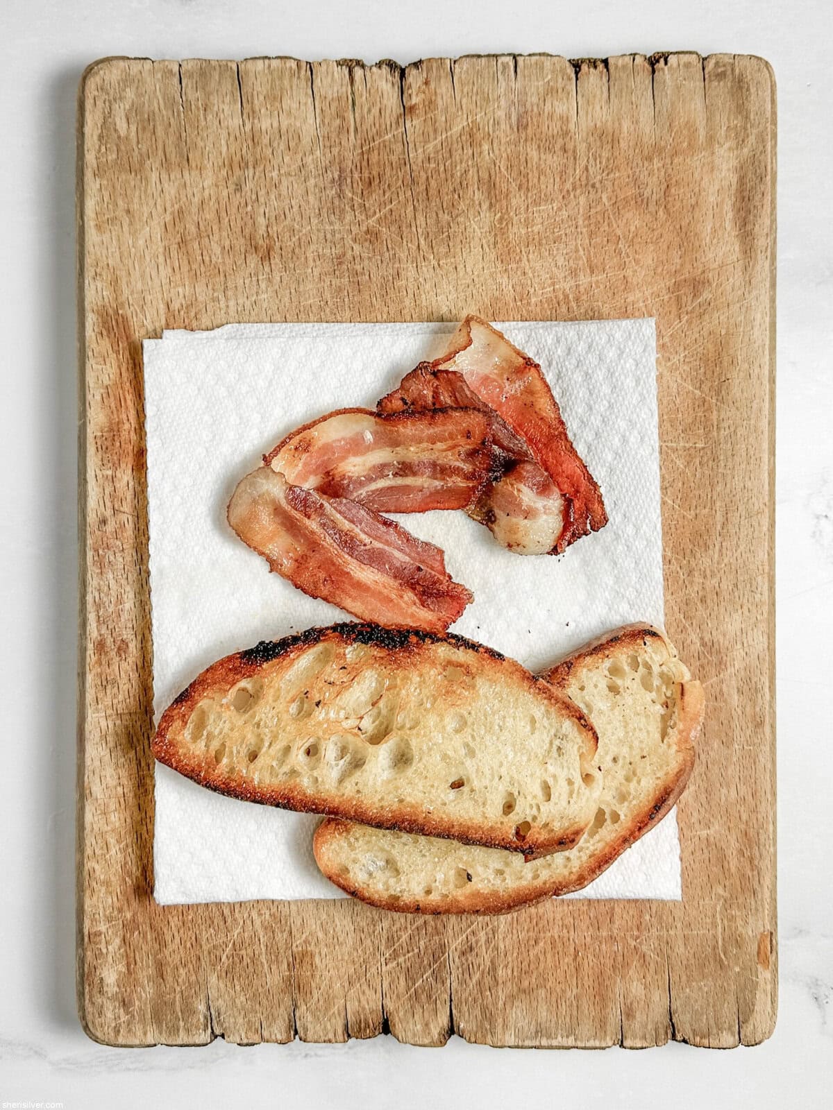 bacon slices and toasted bread for chicken club chopped salad on a cutting board