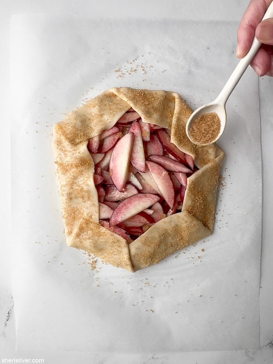 unbaked easy peach galette sprinkled with raw sugar