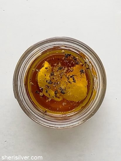 Dressing ingredients—olive oil, vinegar, Dijon, and maple syrup—in a glass jar