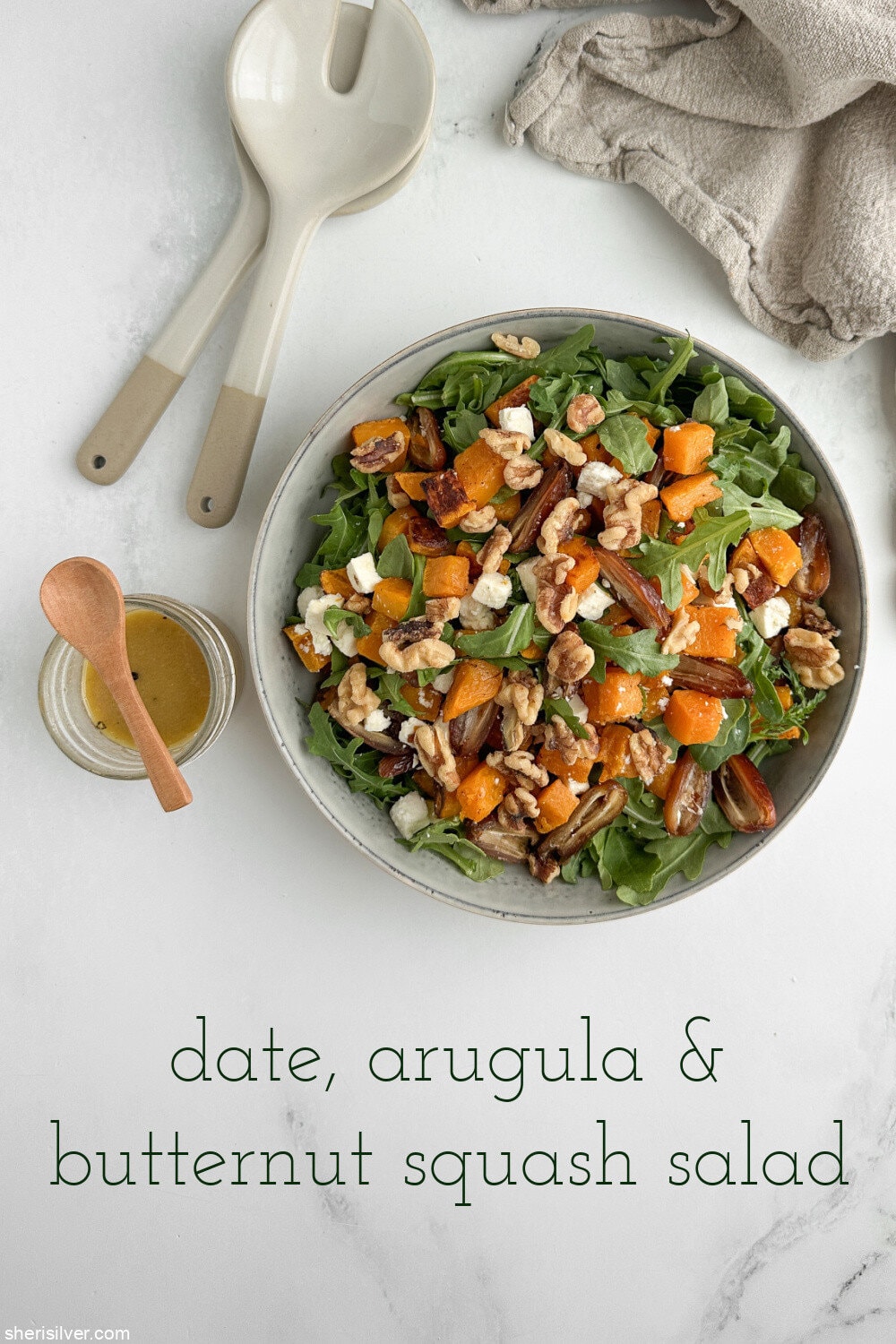 Finished butternut squash salad with dates, arugula, walnuts, and feta in a ceramic serving bowl