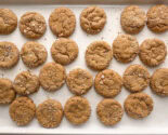 Freshly baked chewy pumpkin cookies with candied ginger on a white baking sheet.
