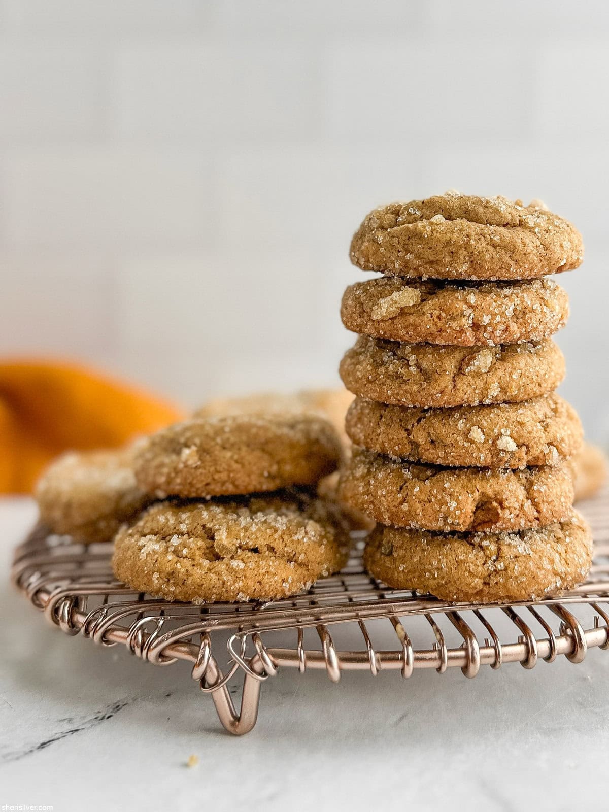 Stack of chewy pumpkin cookies cooling on a metal rack after baking