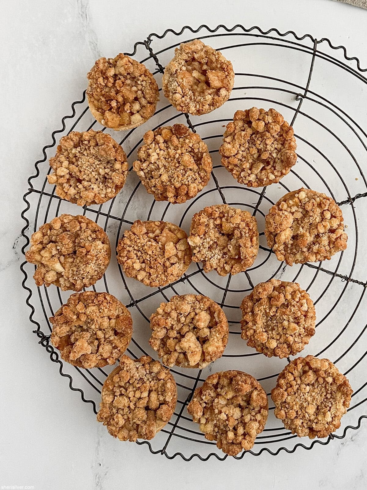 Apple streusel pie cookies arranged on a large round vintage wire cooling rack.”