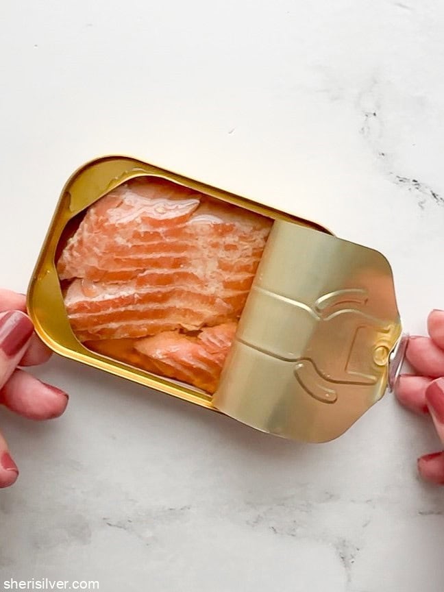 Close-up of smoked salmon in the tin with the top partially rolled back.