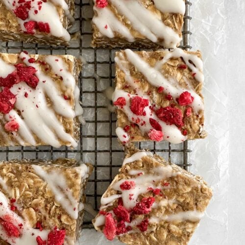 Close-up overhead of a few finished vanilla tahini protein oat bar showing texture and berry topping.