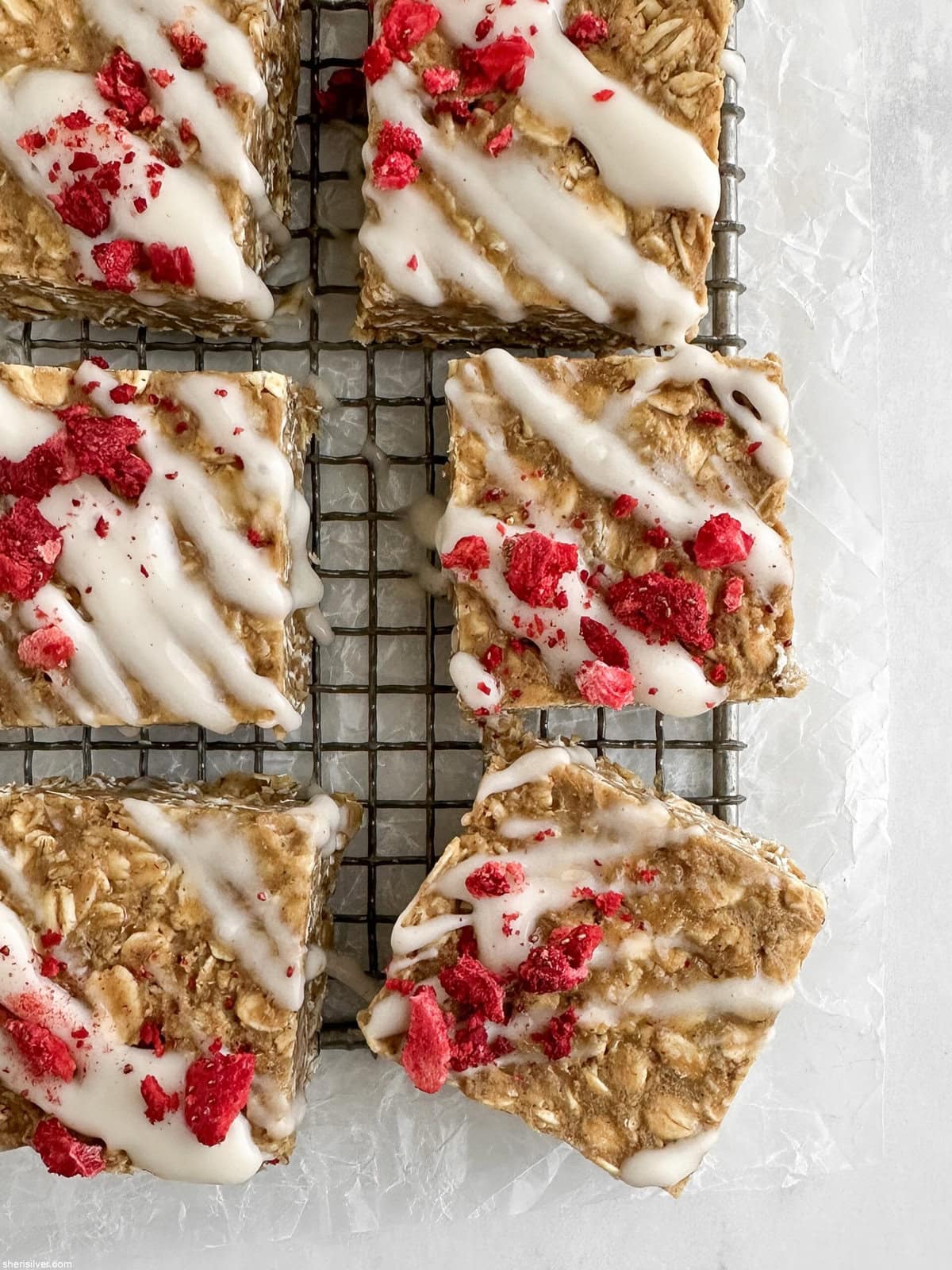 Close-up overhead of a few finished vanilla tahini protein oat bar showing texture and berry topping.
