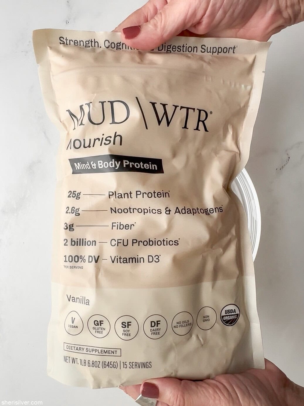 Overhead shot of a bag of MUD\WTR Nourish Vanilla Protein Blend on a marble surface.