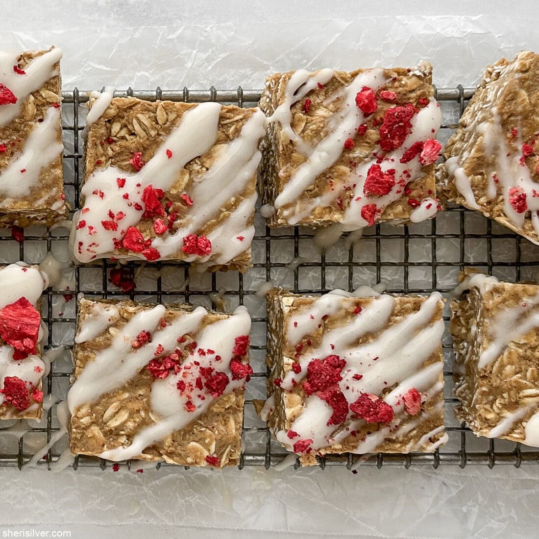 Close-up overhead of a few finished vanilla tahini protein oat bar showing texture and berry topping.