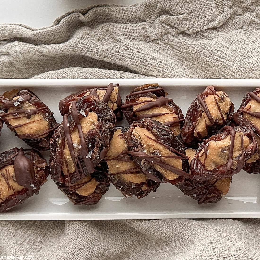Overhead shot of finished stuffed dates on a white tray on a linen napkin.