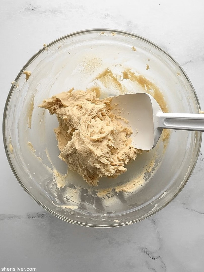 Cream cheese hamantaschen dough in a mixing bowl with a white spatula