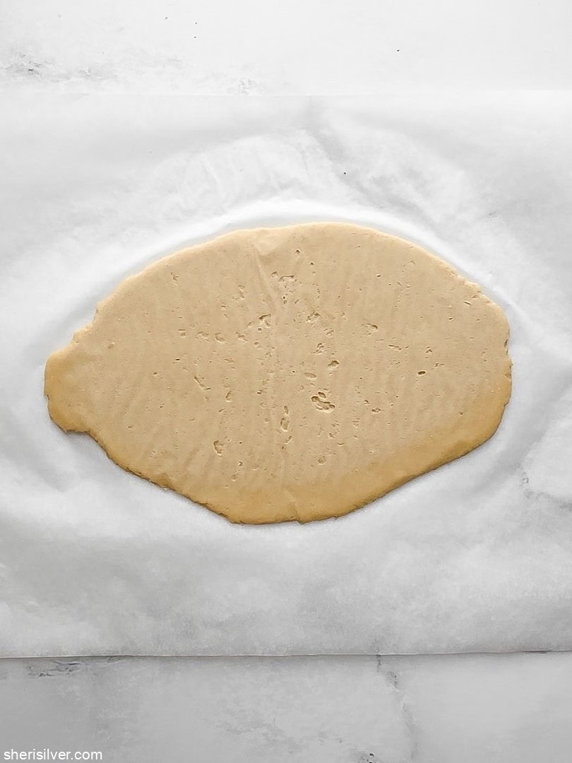 Hamantaschen dough rolled to 1/4-inch thickness on a parchment sheet