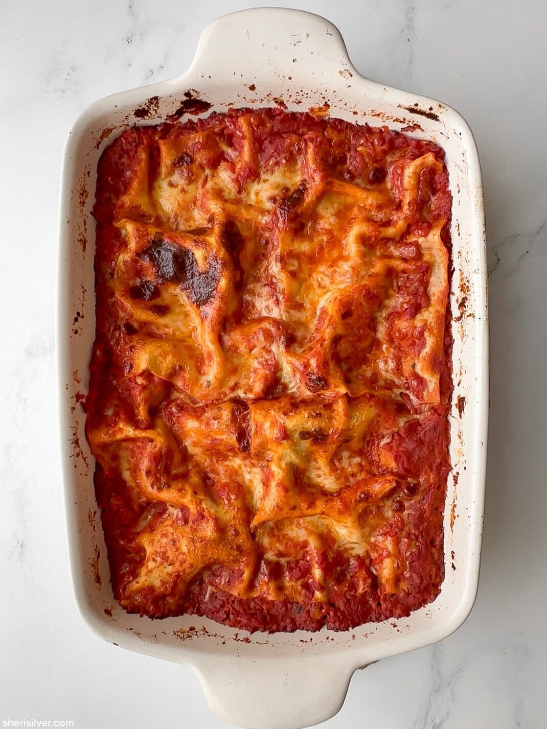 Whole baked lasagna with melted, lightly browned cheese on top.