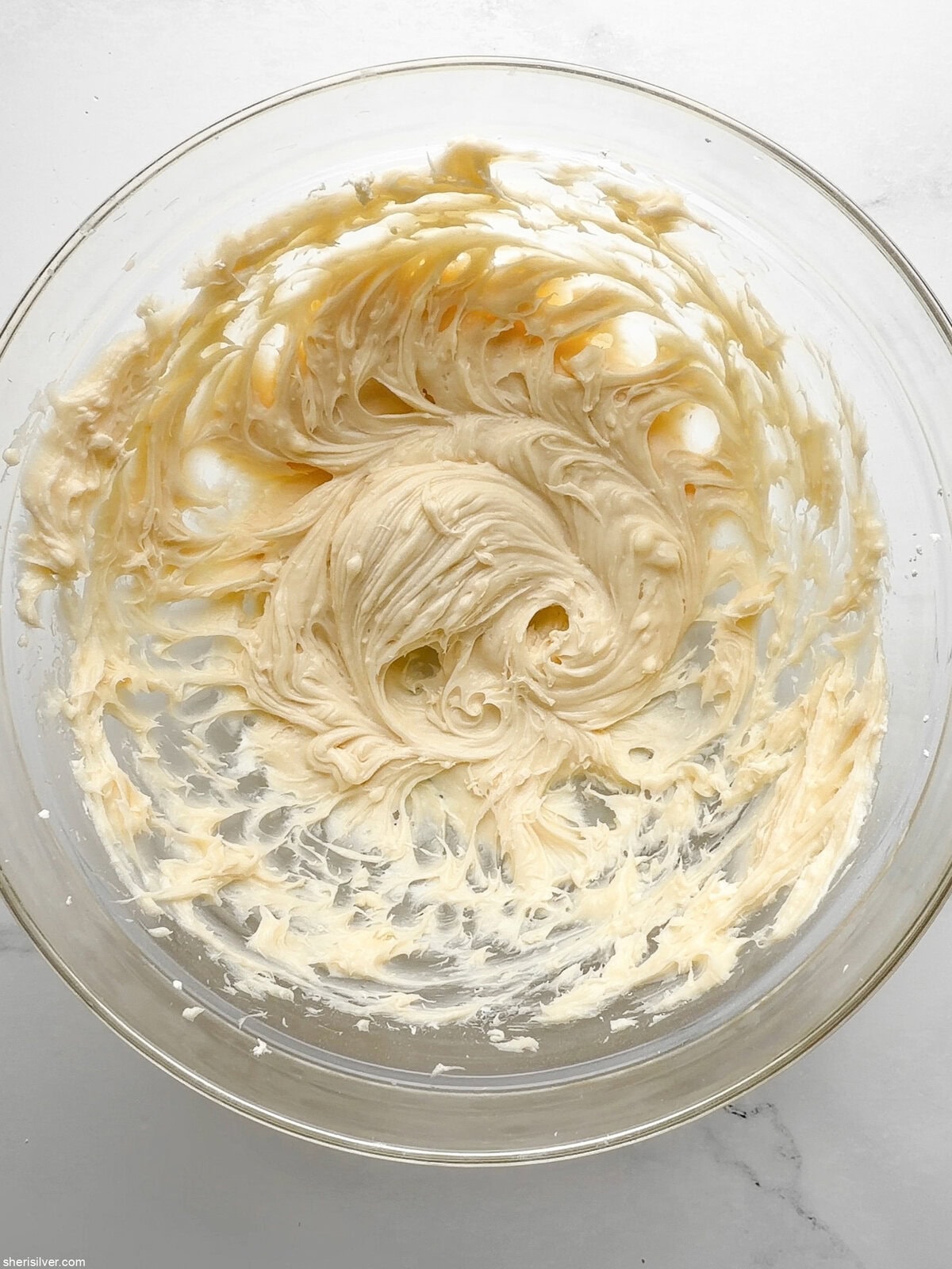 Glass bowl of whipped cream cheese frosting, ready to spread on carrot snacking cake