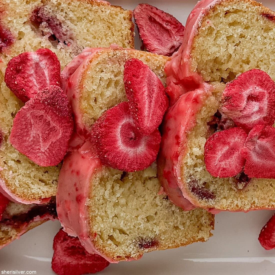 Close-up of sliced strawberry lemon loaf cake showing jammy strawberry pockets and pink glaze