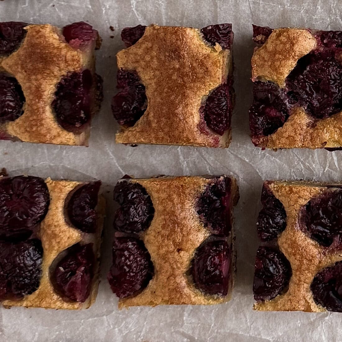 Close-up of cherry brown butter bars showing whole cherries baked into golden brown butter filling